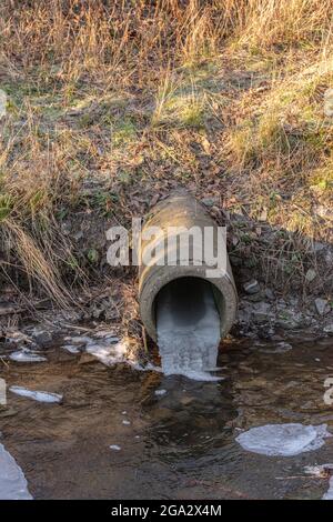 Wasserleitung mit gefrorenem Wasser in einem kleinen Bach Stockfoto