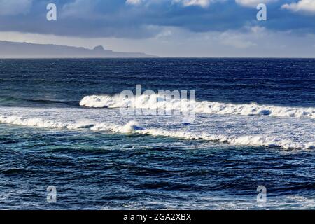 Meereslandschaft mit Wellen, die von einem Aussichtspunkt im Ho'okipa Beach Park brechen, mit Blick auf die Küste in der Ferne und einem bewölkten Himmel in der Nähe von Paia Stockfoto