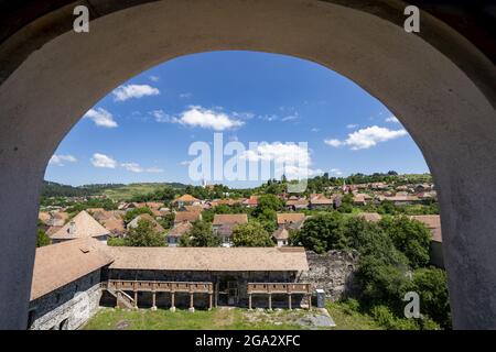 Blick auf die Stadt und das mittelalterliche Schloss Cetatea Bethlen von Racos durch einen Torbogen; Racos, Siebenbürgen, Rumänien Stockfoto