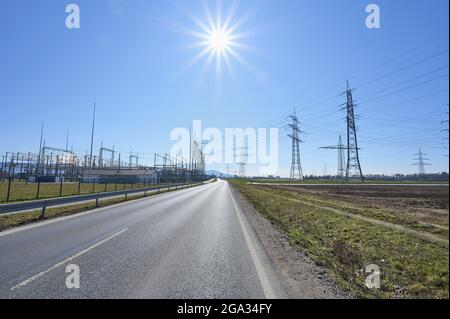 Straße mit Strommasten und Umspannwerk auf dem Land; Hessen, Deutschland Stockfoto