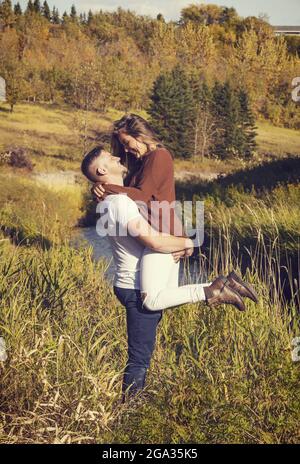 Ehemann und Ehefrau verbringen gemeinsam eine gute Zeit im Freien in der Nähe eines Baches in einem Stadtpark; Edmonton, Alberta, Kanada Stockfoto