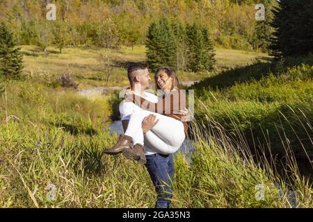 Ehemann und Ehefrau verbringen gemeinsam eine gute Zeit im Freien in der Nähe eines Baches in einem Stadtpark; Edmonton, Alberta, Kanada Stockfoto