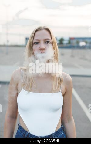 Blonde Frau in der Stadt mit elektronischer Zigarre Vaping Stockfoto