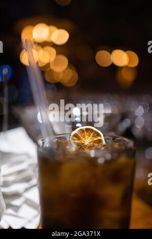 Kalter Eistee mit getrockneten Zitrusfrüchten und Cocktail-Strohschlauch im Glas Stockfoto