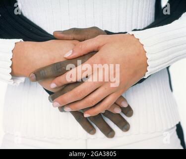 Hände eines kaukasischen Weibchens und eines afroamerikanischen Mannes sind miteinander verflochten; Studio Stockfoto