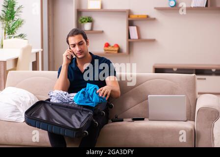 Junger Mann, der sich zu Hause auf die Reise vorbereitet Stockfoto