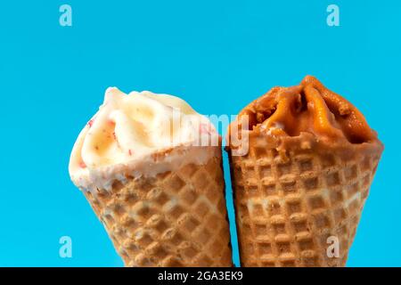 Zwei-Kegel-Eis mit Karamell und weißer Schokolade auf blauem Hintergrund. Stockfoto