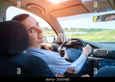 Der junge Kaukasusmann mit einem amputierten Arm fährt ein Auto mit einer Prothese Stockfoto