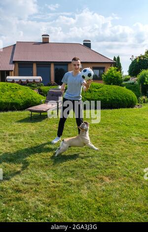 Mann mit ampuiertem Arm und Prothese, der im Hinterhof mit seinem Hund spielt Stockfoto