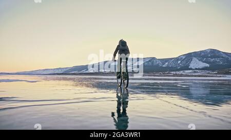 Der Mann fährt mit dem Fahrrad auf dem Eis. Eis des gefrorenen Baikalsee. T-Stück Stockfoto
