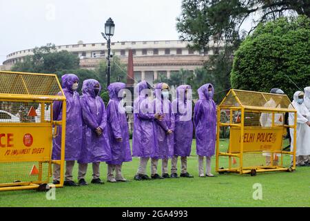 Neu-Delhi, Indien. Juli 2021. Die Polizei von Delhi trägt Gesichtsmasken und Regenmäntel, während sie während des Monsunregens in Vijay Chowk im Dienst ist. Starke Regenfälle haben zur Wasserabholzungen auf der Straße in der Landeshauptstadt geführt. Kredit: SOPA Images Limited/Alamy Live Nachrichten Stockfoto