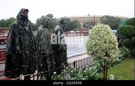 Neu-Delhi, Indien. Juli 2021. Personal der Central Reserve Police Force (CRPF), das Gesichtsmasken und Regenmäntel trug, während er während des Monsunregens in Vijay Chowk im Dienst war. Starke Regenfälle haben zur Wasserabholzungen auf der Straße in der Landeshauptstadt geführt. Kredit: SOPA Images Limited/Alamy Live Nachrichten Stockfoto