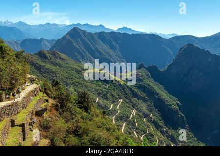 Machu Picchu inka-Ruinenlandschaft vom Sonnentor aus gesehen, mit Touristen, die den letzten Teil der Inka Trail Wanderung, Cusco, Peru, machen. Stockfoto