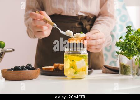 Frau macht leckere Bruschettas mit Feta-Käse auf dem Tisch in der Küche, Nahaufnahme Stockfoto