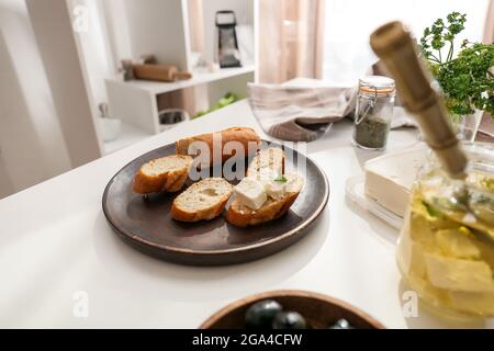 Teller mit leckeren Bruschettas mit Feta-Käse auf dem Tisch in der Küche Stockfoto