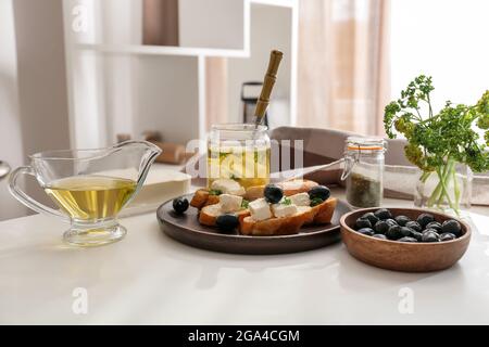 Teller mit leckeren Bruschettas mit Feta-Käse und Zutaten auf dem Tisch in der Küche Stockfoto
