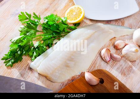 Rohes Kabeljaufilet mit Knoblauch und Zitrone auf Holzoberfläche Stockfoto