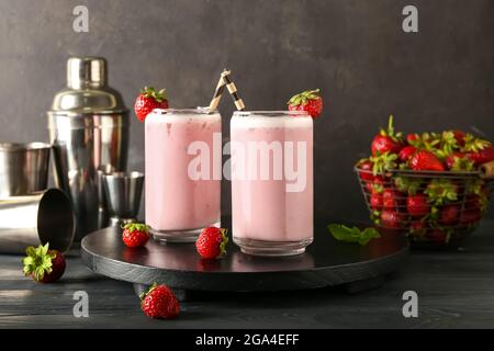 Komposition mit Gläsern Erdbeer Pina Colada Cocktail, Beeren und Shaker auf Holztisch Stockfoto