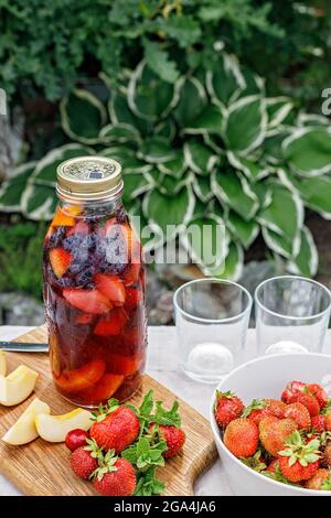 Ein erfrischender Punsch aus Bio-Früchten und Beeren. Erfrischendes Getränk im Sommer mit Eis. Gesunde vegetarische Speisen und Getränke. Pfirsiche, Erdbeeren, Stockfoto