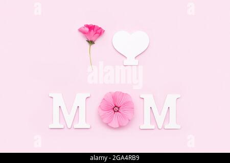 Ich liebe Mama. Abstrakte Liebeserklärung aus weißen Buchstaben und Blumen auf rosa Hintergrund. Kreatives Konzept Muttertag, Grußkarte, po Stockfoto