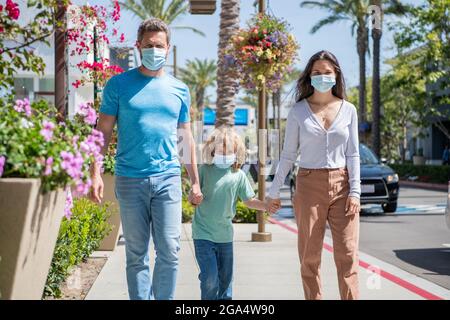 Eltern mit Kind Junge tragen medizinische Maske. Mama Vater und Sohn. Lebensversicherung. Adoption und Nächstenliebe. Stockfoto