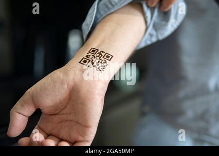 Der Mann zeigt seine Hand mit einem qr-Code, einer Bestätigung der Impfung gegen das Covid 19 Coronavirus. Temporäre Tätowierung am Handgelenk, Armes Stockfoto