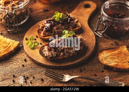 Gezogene Ente mit karamellisierten Zwiebeln auf rustikalem Hintergrund Stockfoto