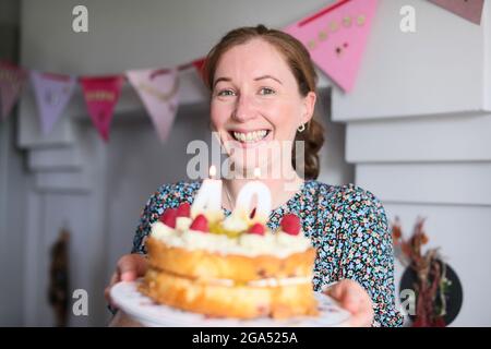 Eine Frau feiert ihren 40. Geburtstag, indem sie die Kerzen auf ihrem Geburtstagskuchen in Armoy, County Antrim, Nordirland, ausbläst. Stockfoto