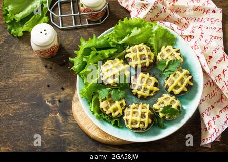 Festliche Vorspeise im Herbst. Mit Kartoffelpüree gebackene Champignons auf einem rustikalen Tisch. Speicherplatz kopieren. Stockfoto