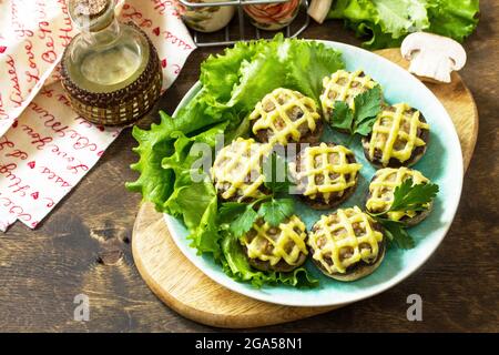 Festliche Vorspeise im Herbst. Mit Kartoffelpüree gebackene Champignons auf einem rustikalen Tisch. Stockfoto