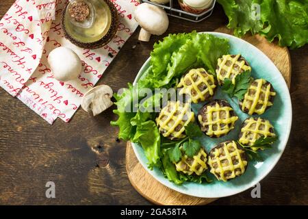 Festliche Vorspeise im Herbst. Mit Kartoffelpüree gebackene Champignons auf einem rustikalen Tisch. Draufsicht flach lay Hintergrund. Speicherplatz kopieren. Stockfoto