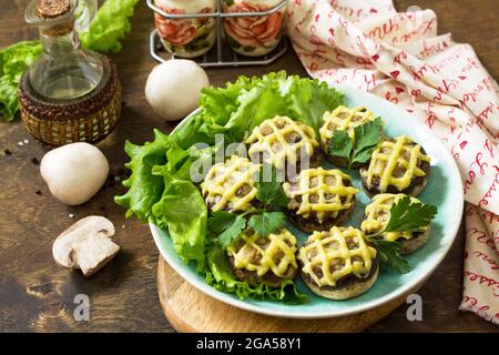 Festliche Vorspeise im Herbst. Mit Kartoffelpüree gebackene Champignons auf einem rustikalen Tisch. Stockfoto