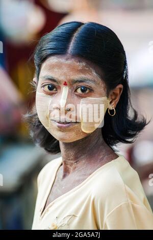 Schöne junge burmesische Mädchen mit Thanaka gelbe Paste auf Wangen und gelbe Augen Posen für Foto, Mandalay, Myanmar Stockfoto