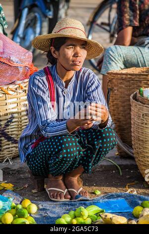 Weibliche Markthändlerin mit Strohhut, geduckt von Früchten auf dem Boden, Kalaw, Myanmar Stockfoto