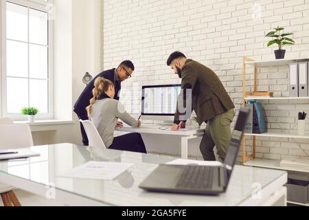 Ein vielseitiges Team von Mitarbeitern, die mit Geschäftstabellen arbeiten und den Umsatz des Unternehmens analysieren Stockfoto