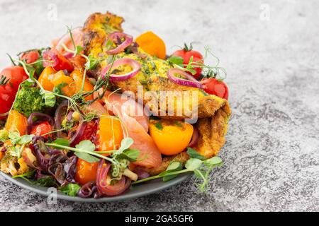 Omelette mit geschmortem Gemüse und Lachs, Tomaten mit Zwiebeln, Brokkoli und rotem Fisch mit Erbsen-Microgreens, leckeres herzhaftes Frühstück Stockfoto