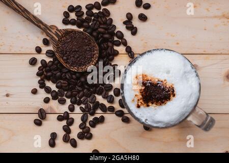 Blick von oben auf den eisgekühlten Kaffeeschaum in der Kaffeetasse auf dem Holzboden. Stockfoto