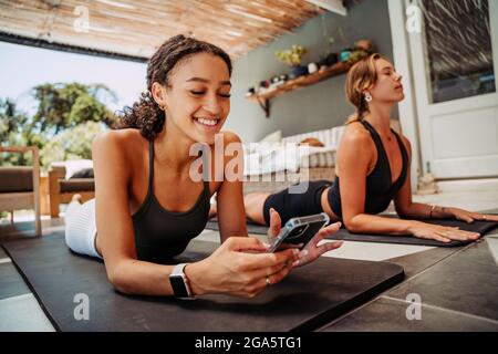 Zwei Freunde kühlen sich ab, nachdem sie eine Dehnung und eine Eingabe auf dem Mobiltelefon ausgeübt haben Stockfoto