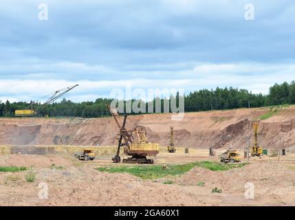 Bagger, Bergbaumaschinen, Radlader und Bulldozer arbeiten im Dolomit-Steinbruch. Blick auf die industrielle Landschaft im Tagebau, wo schwere Industrie mac Stockfoto