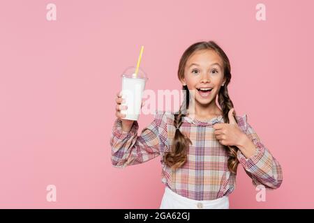 Kind mit Milchshake, die wie Geste isoliert auf Rosa zeigt Stockfoto