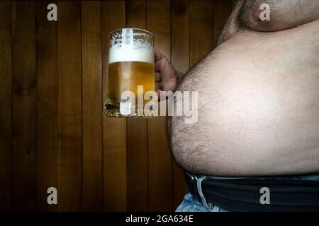 Ein Mann mit einem großen Bauch und einem Becher Bier in der Hand Stockfoto