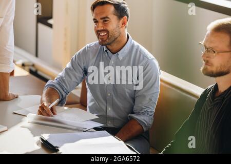 Männlicher Vorstandssitzender in der Sitzung. Junger Mann, der die Diskussion in einer Brainstorming-Sitzung beim Start aufmerksam gemacht hat. Stockfoto