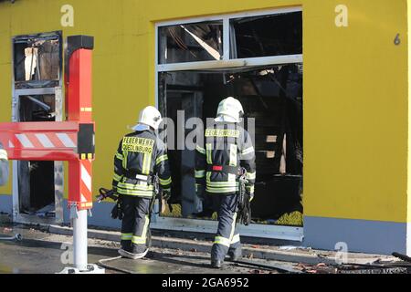 Quedlinburg, Deutschland. Juli 2021. Feuerwehrleute stehen vor dem ausgebrannten Supermarkt. In der Nacht waren etwa 77 Feuerwehrleute vor Ort, um den Markt kontrolliert verbrennen zu lassen. Über die Brandursache und die Höhe des Schadens ist bisher nichts bekannt. Quelle: Matthias Bein/dpa-Zentralbild/dpa/Alamy Live News Stockfoto