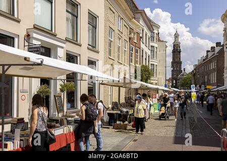 ZUTPHEN, NIEDERLANDE - 25. Jul 2021: Kleine Buchmesse im Zentrum der historischen mittelalterlichen Hansestadt während der COVID-19 Pandemie mit Wijnhuistoren dahinter. Stockfoto