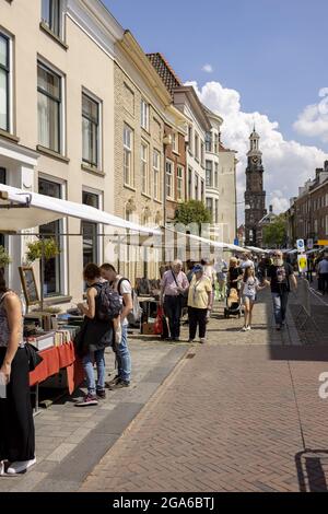 ZUTPHEN, NIEDERLANDE - 25. Jul 2021: Street Small Book Fair im Zentrum der historischen Hansestadt während der COVID-19 Pandemie mit Wijnhuistoren dahinter. Stockfoto