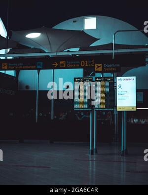 Reisen, Business, Werbung - Bildschirme mit Informationen über die an- und Abflüge von Flügen an einem Flughafen und ein Poster über covid Maßnahmen Stockfoto