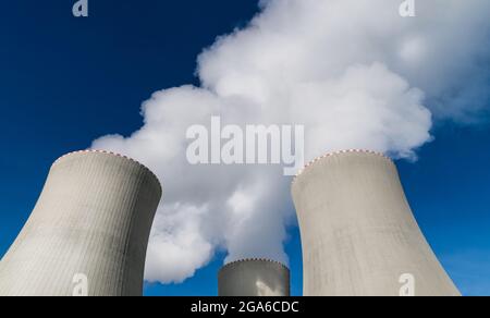 Nahaufnahme der Kühltürme des Kernkraftwerks, die weiße Wasserdampfwolken ausstoßen. Entfernen der Wärme. Modernes Kraftwerk am blauen Himmel. Ökologie. Stockfoto