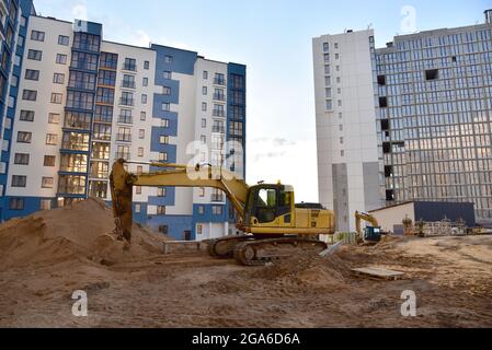 Bagger auf Erdarbeiten. Verlegung von Heizrohren und Regenwasser in den Graben. Installation von Betonbrunnen, сhambers, Schächten. Turmdrehkrane im Baugewerbe Stockfoto