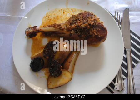 Gebratener und geschmorter putendrumstick, serviert mit Apfel und Pflaumen Stockfoto