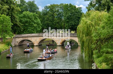 CAMBRIDGE ENGLAND RIVER CAM TOURISMUS UND TOURISTEN AN DER TRINITY BRIDGE AN EINEM SOMMERWOCHENENDE EINE FLOTTILLE VON PUNTS UND PASSAGIEREN Stockfoto